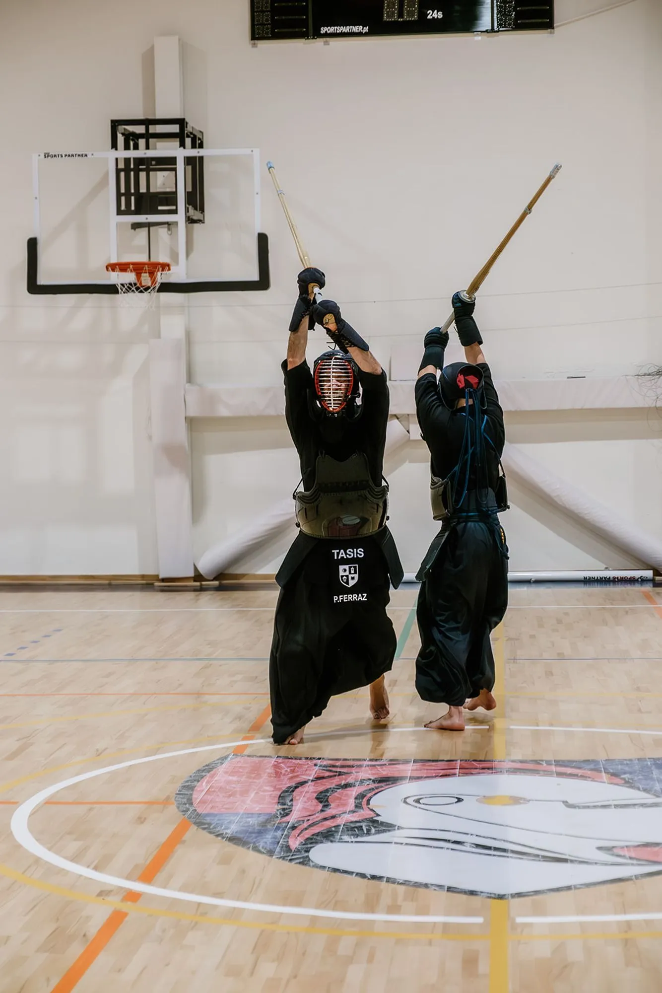 Two kendoka mid-strike, shinai overhead, seen from behind