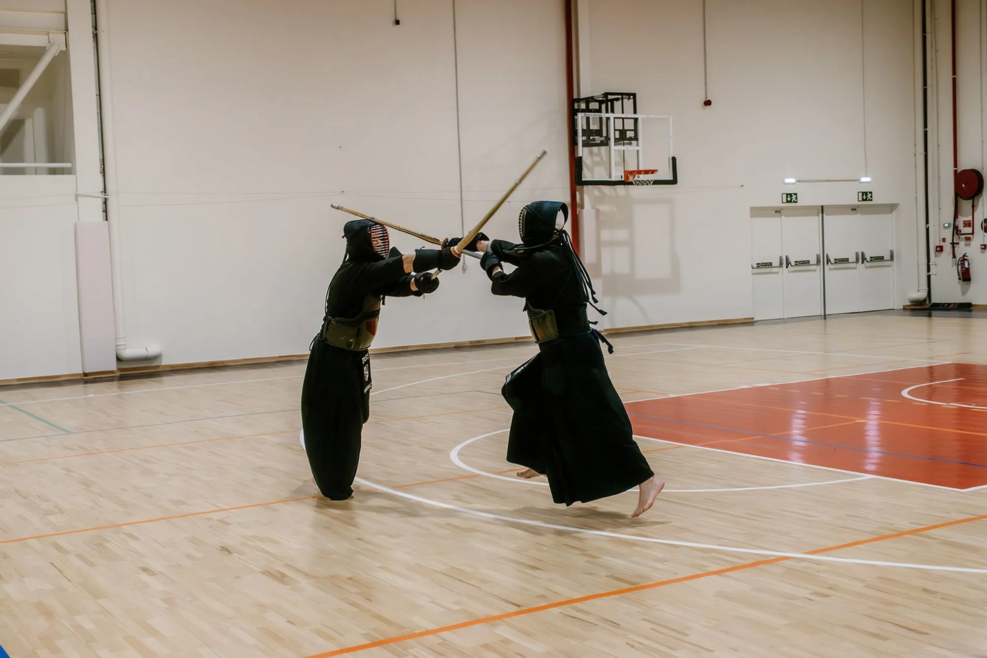Two kendoka facing off across the court