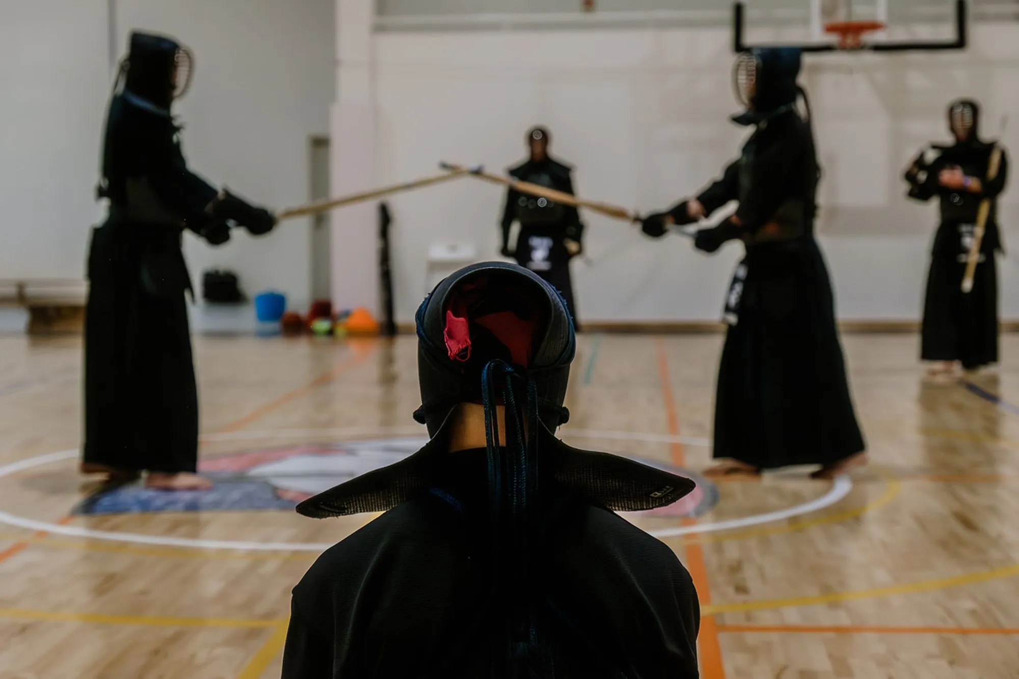 A kendoka in men seen from behind, others training beyond