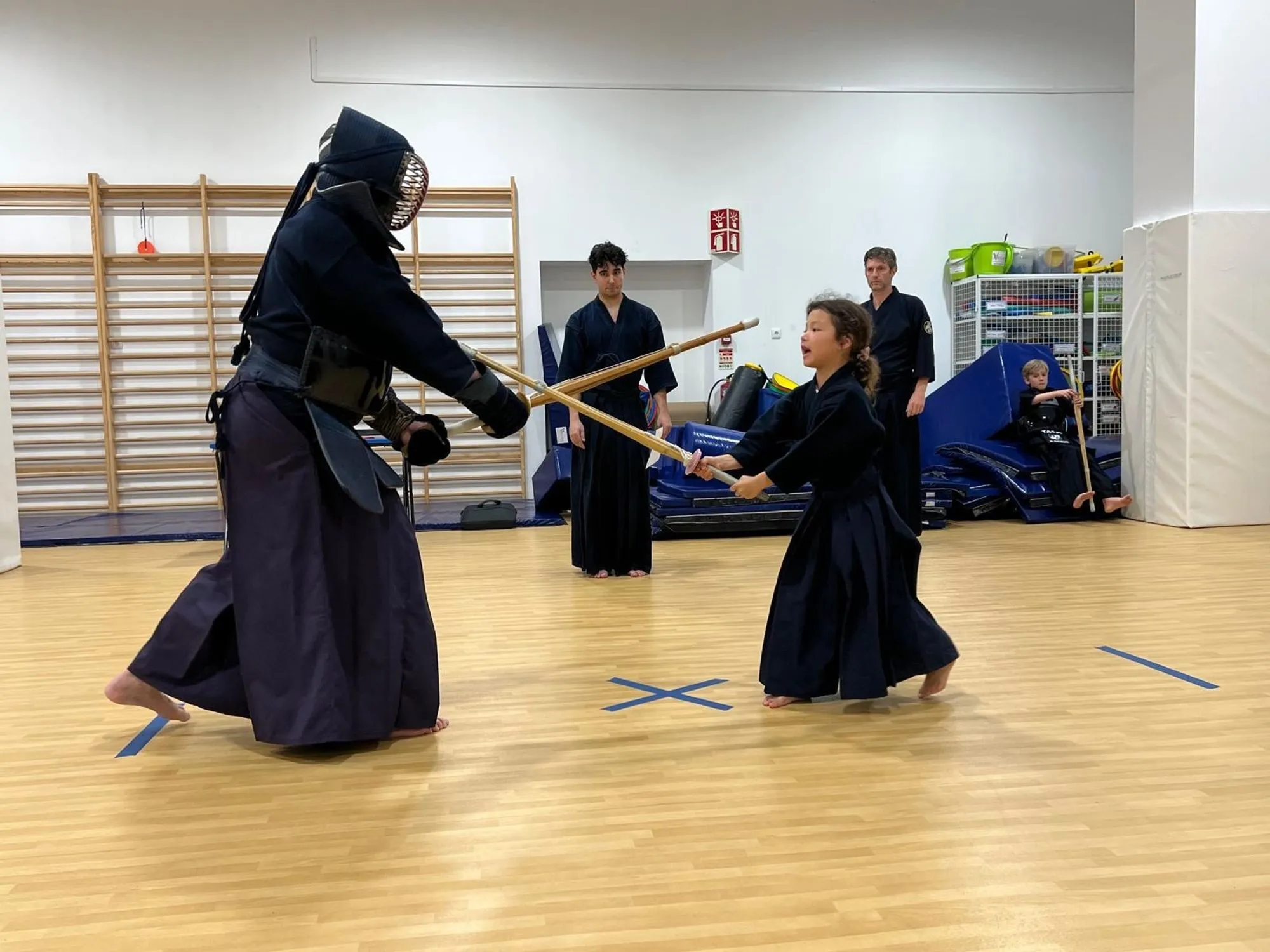 Two kendoka sparring in front of the wall bars