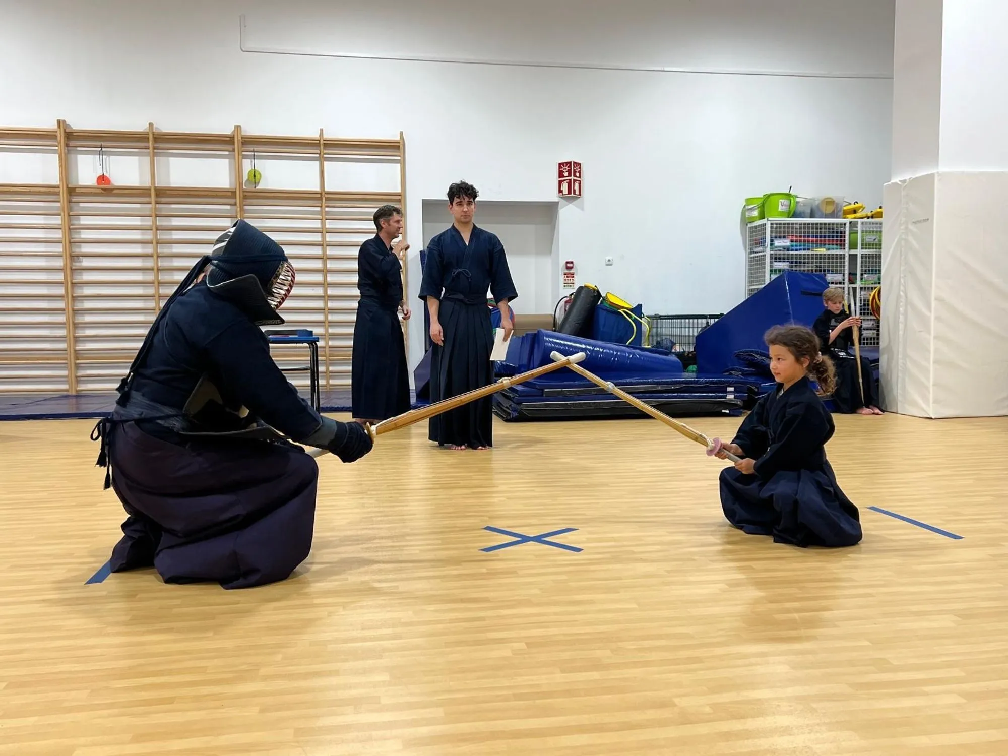 A match in progress, a young kendoka kneeling at the side