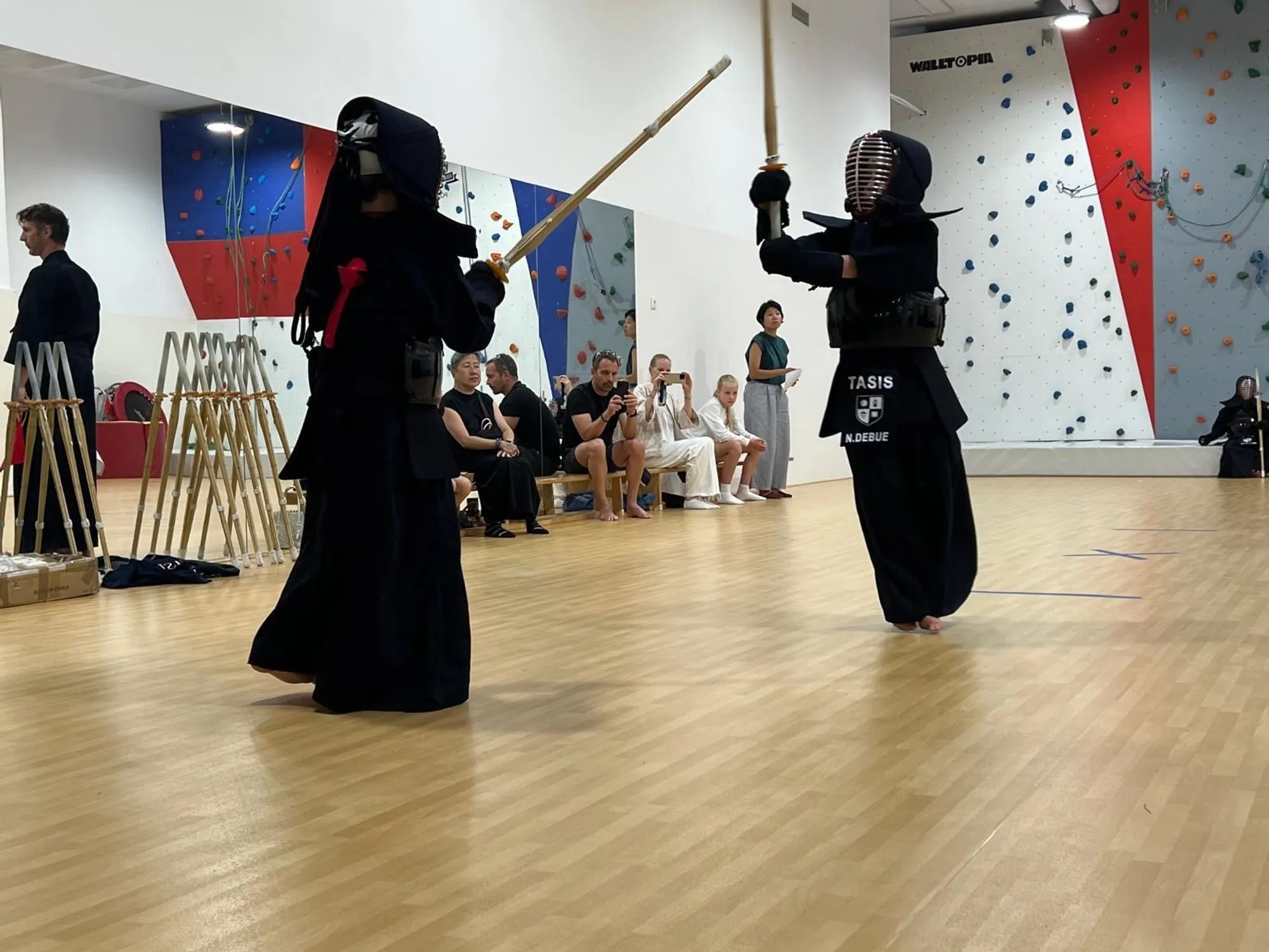 A kendoka striking, climbing wall in the background