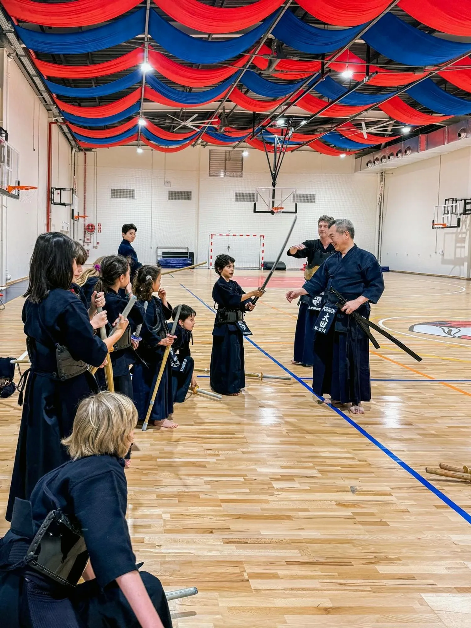 An instructor guiding young kendoka through a drill